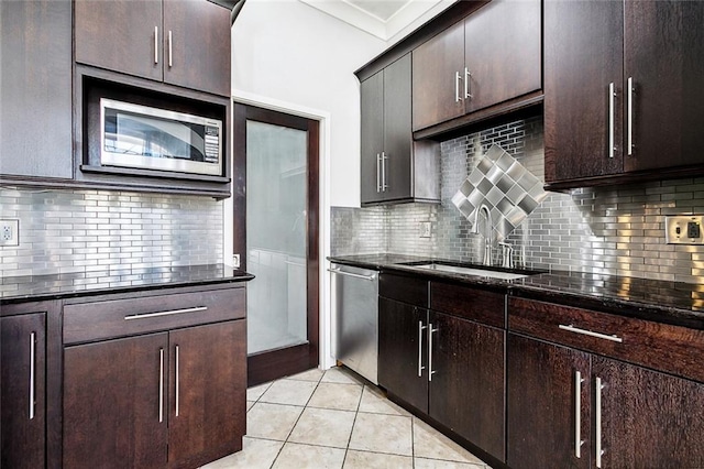 kitchen with appliances with stainless steel finishes, tasteful backsplash, dark stone counters, and sink