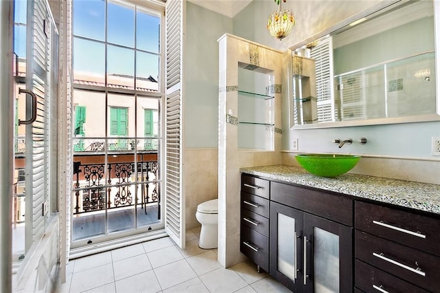 bathroom featuring toilet, vanity, tile patterned floors, and tile walls