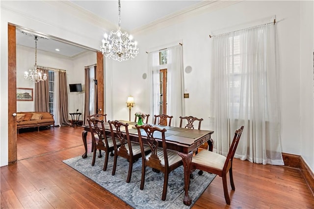 dining room with a notable chandelier, wood-type flooring, crown molding, and a wealth of natural light