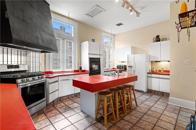 kitchen featuring appliances with stainless steel finishes, a center island, white cabinetry, and wall chimney exhaust hood