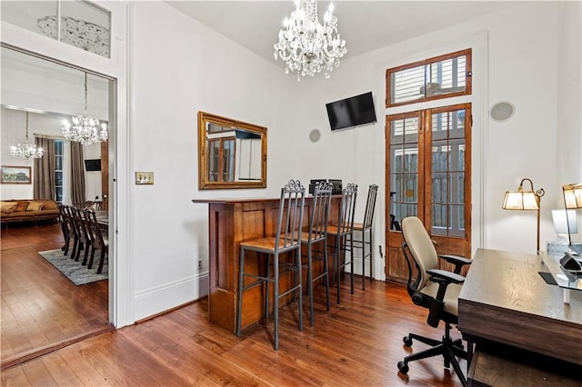 office space featuring hardwood / wood-style flooring, a high ceiling, and an inviting chandelier