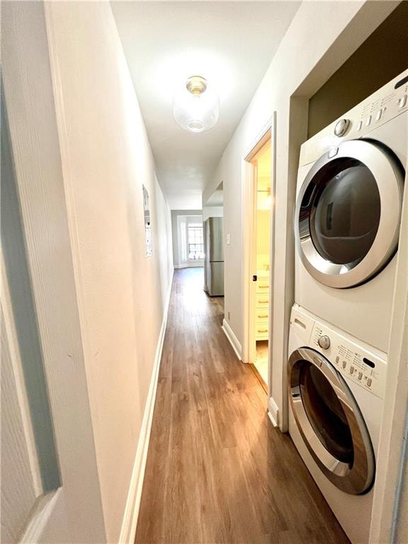 laundry room featuring hardwood / wood-style floors and stacked washer and clothes dryer