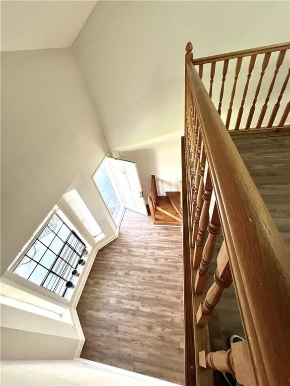 stairs featuring hardwood / wood-style floors and high vaulted ceiling