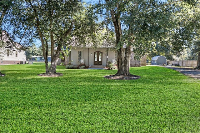 view of front of home featuring a front lawn, a storage shed, and french doors