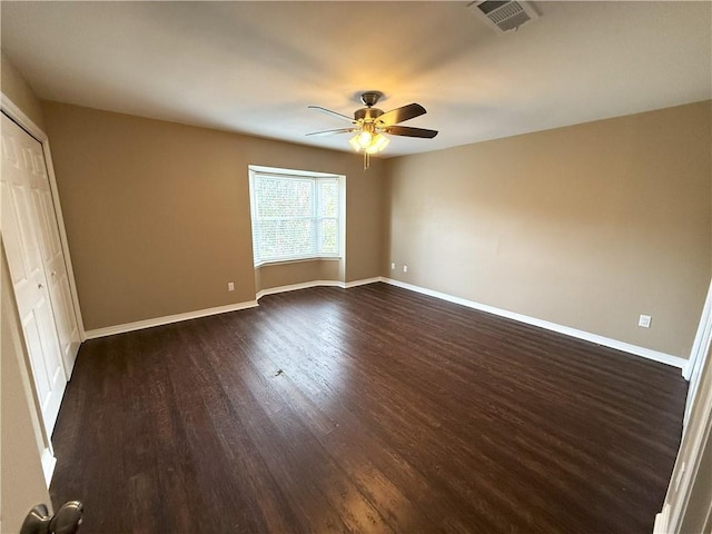 unfurnished bedroom with ceiling fan, dark wood-type flooring, and a closet