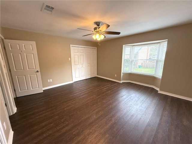 unfurnished bedroom featuring ceiling fan, dark hardwood / wood-style flooring, and a closet