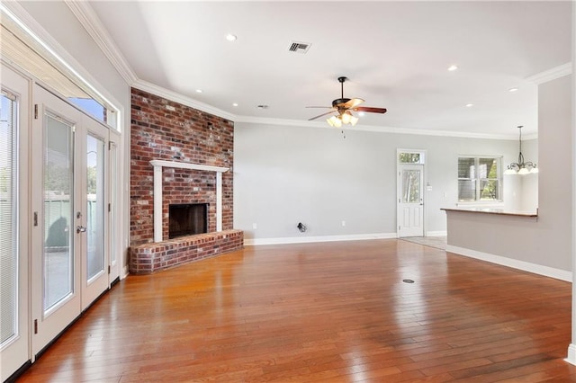 unfurnished living room with ornamental molding, ceiling fan with notable chandelier, and hardwood / wood-style flooring