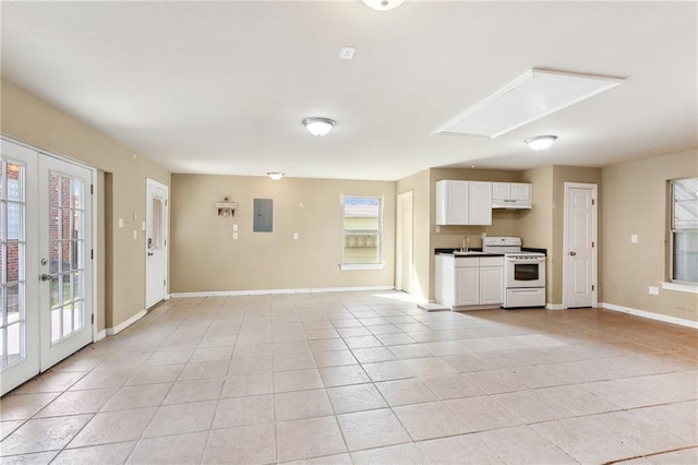 unfurnished living room featuring electric panel, french doors, light tile patterned floors, and sink