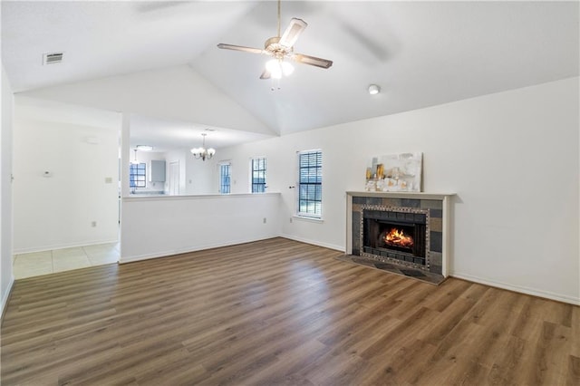 unfurnished living room featuring a tile fireplace, ceiling fan with notable chandelier, dark hardwood / wood-style floors, and high vaulted ceiling