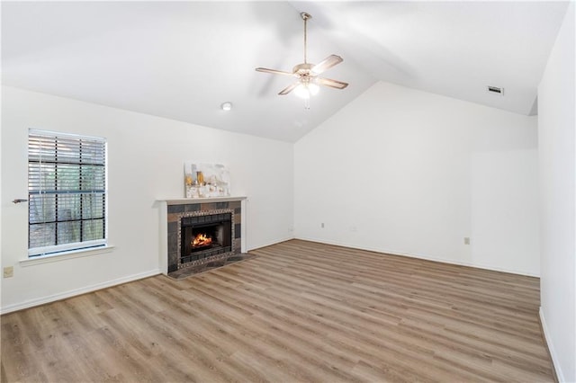 unfurnished living room with a tiled fireplace, ceiling fan, light hardwood / wood-style flooring, and high vaulted ceiling