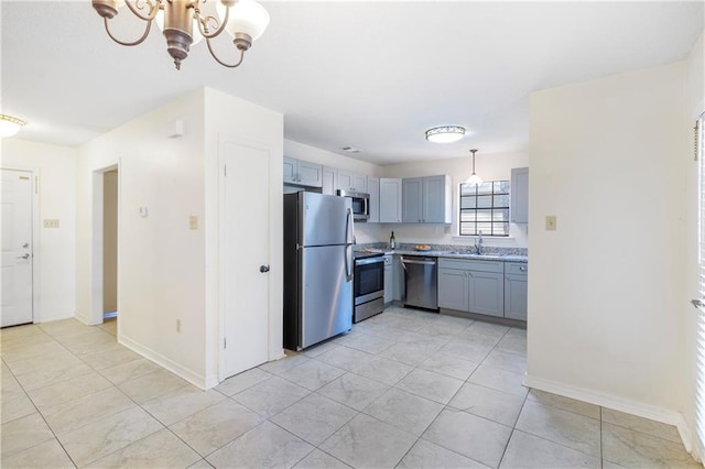 kitchen with appliances with stainless steel finishes, hanging light fixtures, a notable chandelier, and sink