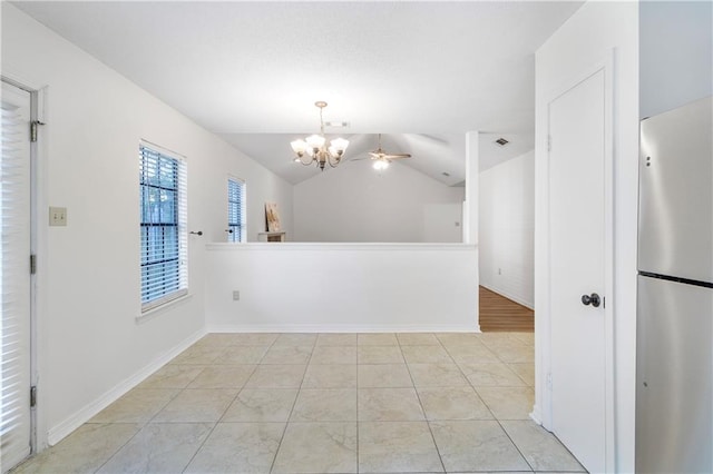 empty room featuring light tile patterned floors, ceiling fan with notable chandelier, and lofted ceiling