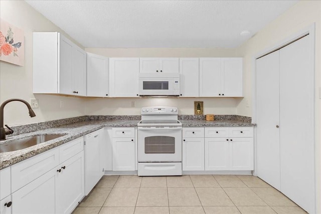 kitchen featuring white appliances, sink, light stone countertops, light tile patterned floors, and white cabinetry