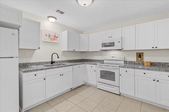 kitchen featuring white cabinetry, sink, light tile patterned floors, and white appliances