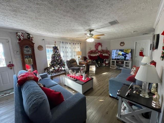 living room featuring a textured ceiling, wood finished floors, visible vents, and a healthy amount of sunlight