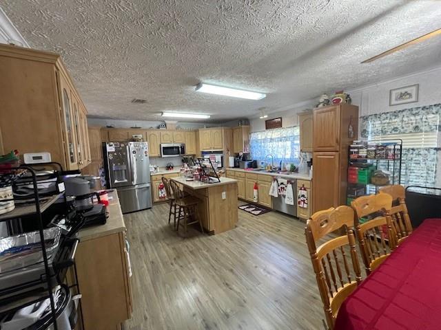 kitchen with a center island, a breakfast bar area, stainless steel appliances, light countertops, and light wood-style flooring