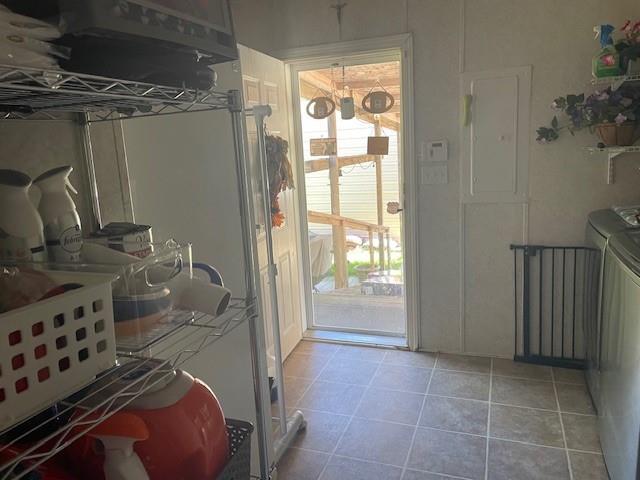 doorway to outside featuring washer and dryer, electric panel, and light tile patterned floors