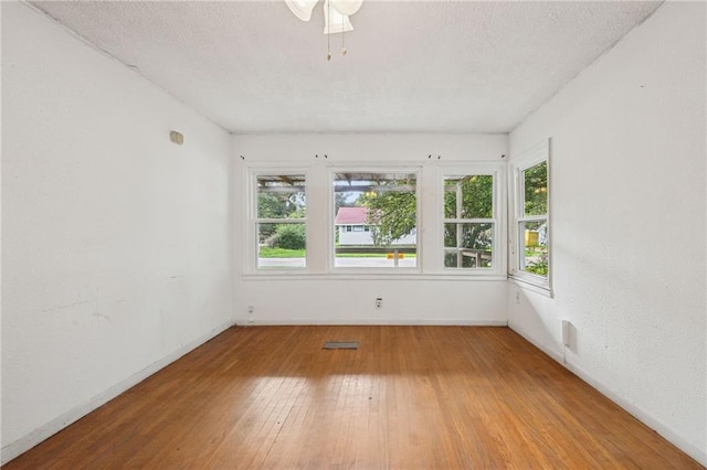 spare room with ceiling fan, wood-type flooring, and a textured ceiling