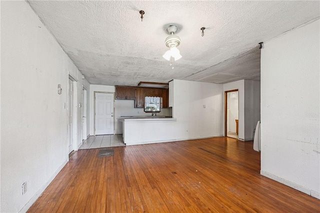 unfurnished living room with light hardwood / wood-style floors and a textured ceiling