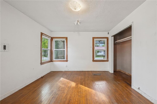 unfurnished bedroom featuring dark hardwood / wood-style flooring, a closet, and multiple windows