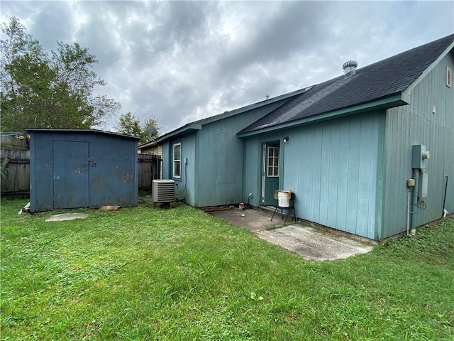 back of house with a yard, central AC unit, and a storage shed