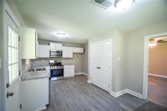 kitchen with sink, white cabinets, stainless steel appliances, and light hardwood / wood-style floors