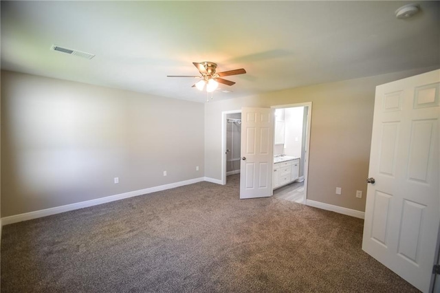 unfurnished bedroom with carpet flooring, ceiling fan, a spacious closet, connected bathroom, and a closet