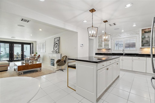 kitchen with a center island, hanging light fixtures, white cabinets, decorative backsplash, and light tile patterned flooring