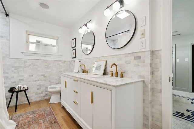 bathroom featuring hardwood / wood-style floors, vanity, toilet, and tile walls