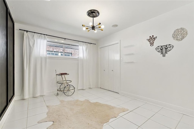 empty room with a notable chandelier and light tile patterned flooring