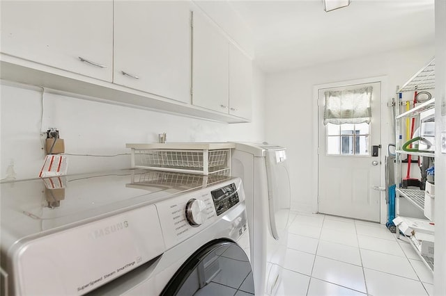 laundry room featuring washer and clothes dryer, light tile patterned floors, and cabinets