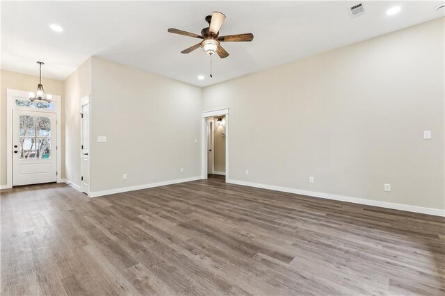 empty room featuring dark wood-type flooring and ceiling fan with notable chandelier