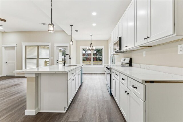 kitchen with an island with sink, appliances with stainless steel finishes, hanging light fixtures, white cabinets, and sink