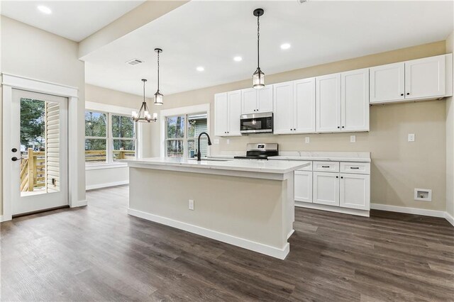 kitchen with decorative light fixtures, sink, white cabinetry, a kitchen island with sink, and appliances with stainless steel finishes