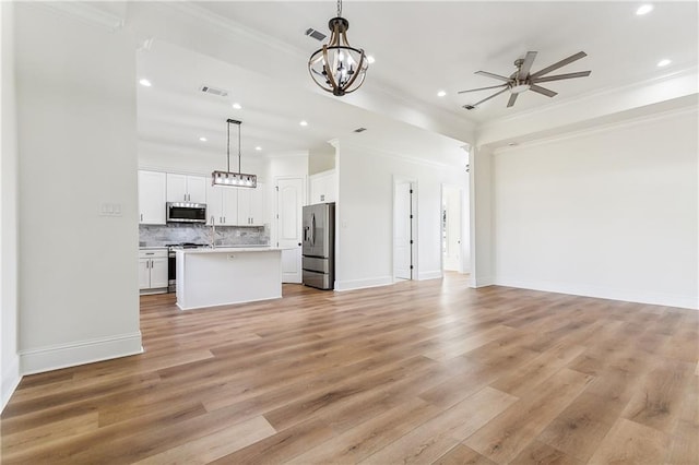 unfurnished living room featuring ornamental molding, ceiling fan with notable chandelier, and light hardwood / wood-style floors