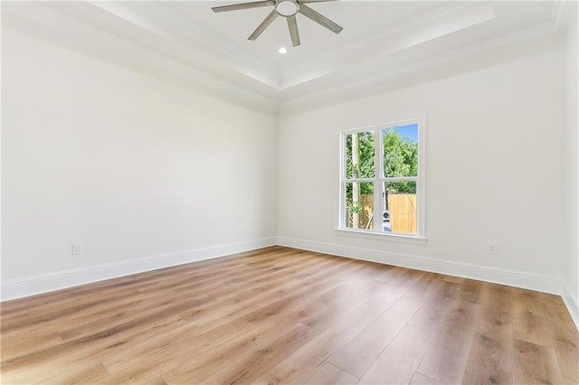 spare room featuring a tray ceiling, light hardwood / wood-style flooring, ornamental molding, and ceiling fan