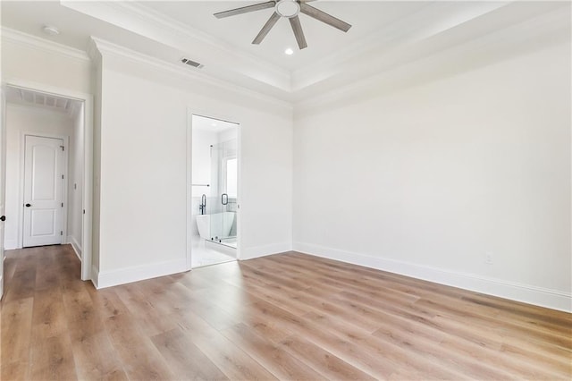 unfurnished bedroom with connected bathroom, crown molding, a raised ceiling, ceiling fan, and light hardwood / wood-style floors