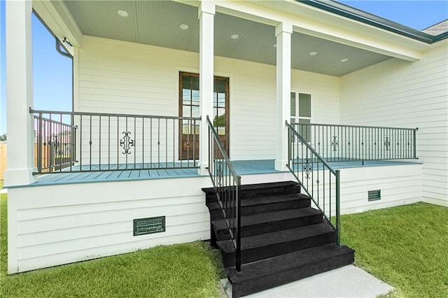 view of exterior entry with covered porch and a lawn