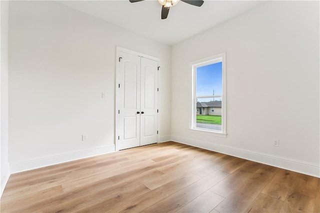 unfurnished bedroom featuring light wood-type flooring, ceiling fan, and a closet