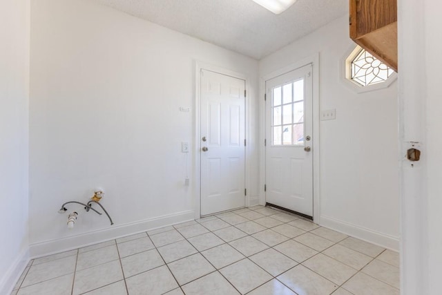 doorway with a textured ceiling and light tile patterned flooring