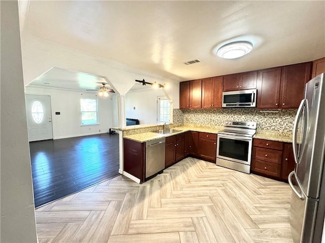 kitchen with ceiling fan, stainless steel appliances, kitchen peninsula, decorative backsplash, and ornamental molding