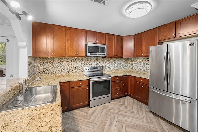 kitchen featuring decorative backsplash, sink, light stone countertops, and stainless steel appliances