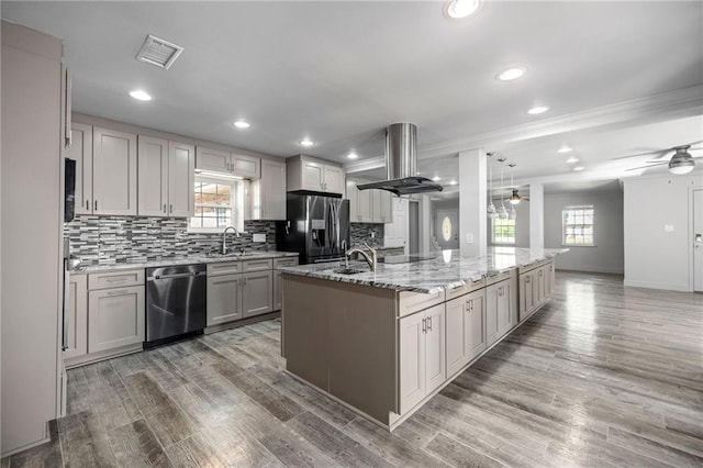 kitchen featuring stainless steel appliances, island range hood, sink, hardwood / wood-style floors, and an island with sink