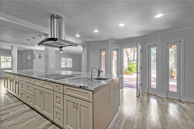 kitchen featuring sink, light stone countertops, island exhaust hood, and a wealth of natural light