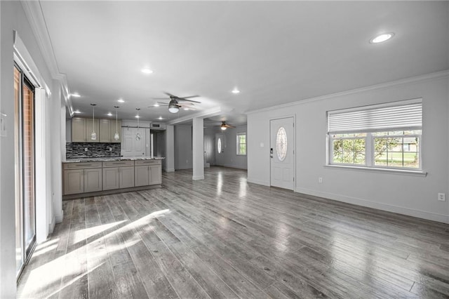 unfurnished living room featuring wood-type flooring, a barn door, ceiling fan, and crown molding