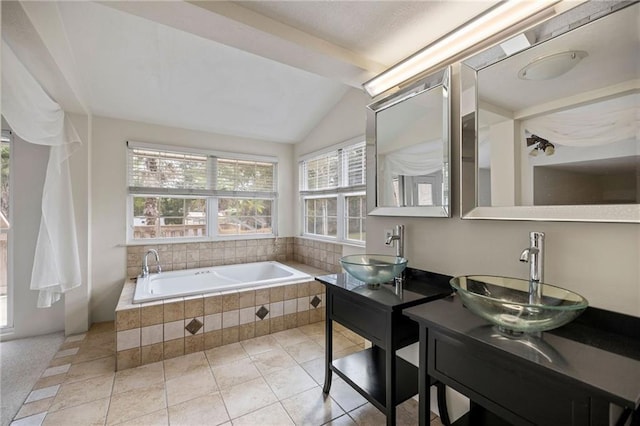 bathroom with tile patterned flooring, vanity, tiled bath, and lofted ceiling