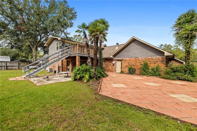 rear view of property featuring a lawn, a patio area, and a wooden deck