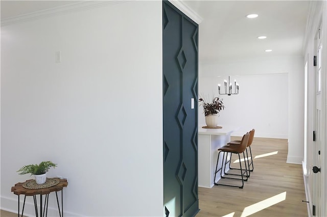 hallway with crown molding, an inviting chandelier, and light wood-type flooring