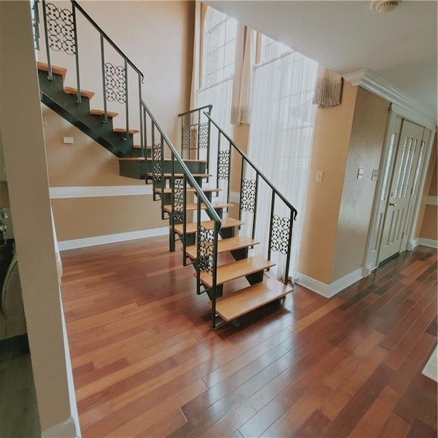 stairs featuring crown molding and hardwood / wood-style flooring