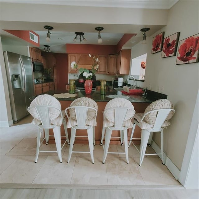 kitchen with kitchen peninsula, stainless steel fridge, and light tile patterned flooring